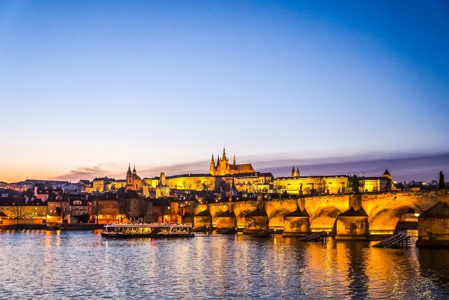 Prague Castle and Charles Bridge lit above the Vltava at dusk